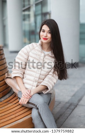 Brunette in a pink quilted jacket and trousers sits near the business center