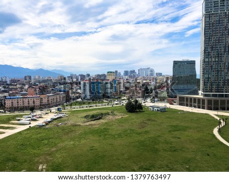 Green park in a modern big city, megalopolis with high glass houses, buildings, skyscrapers against the blue sky of the mountains on a tropical warm summer resort, rest.