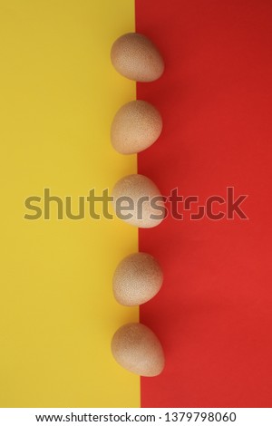 Five eggs of Guinea fow positioned in the middle of the picture on yellow and red background.
