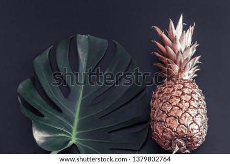 Summer tropical background with Golden pineapple and tropical leaf on pastel black background, summer creativity and style concept
