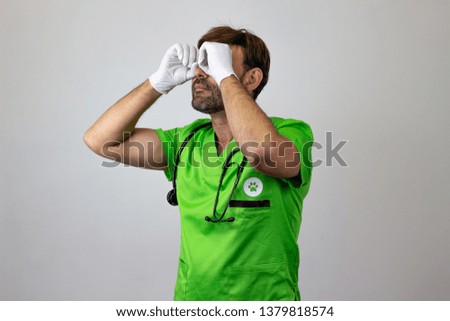 Photography of a veterinary doctor pretending to use binoculars, facing forwards and looking at the horizon