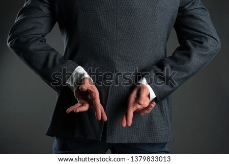 The liar business man. A man with crossed finger behind his back is giving a false promises concept. Deceitful person. Royalty-Free Stock Photo #1379833013