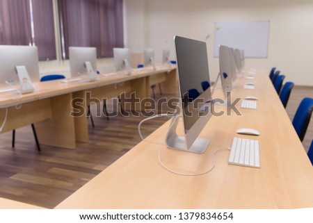 Modern office with computers on desks. Empty computer room in college. Interior of classroom with computers. Concept of corporate working space. Royalty-Free Stock Photo #1379834654