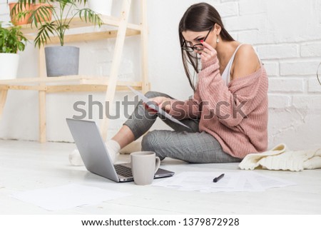 Young woman sits on the floor in a Scandinavian apartment interior with a laptop, studying law, freelance girl at work, distance learning student, online employment, paperwork and outsourcing concept