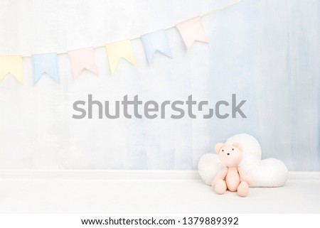 Pastel baby background in soft light blue and pink colors with teddy bear cloud toy figure near paint wall in child room. Newborn concept greeting card. Place for text