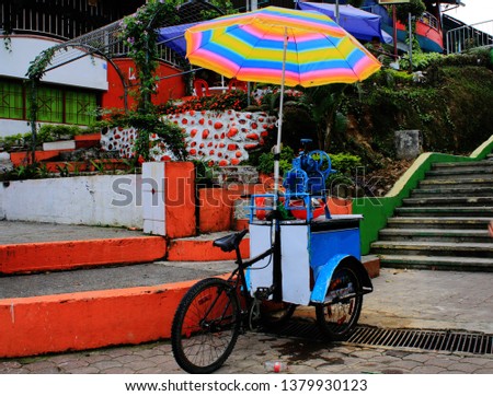 Local small shop on a bike selling drink under a bright and colorful umbrella in south america
