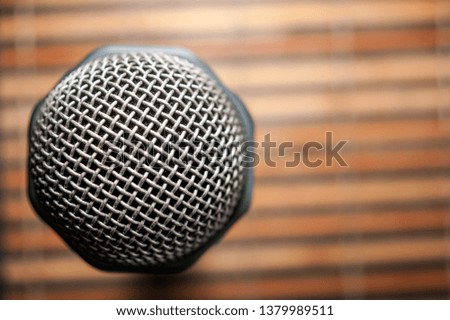 Top-Down View of A Microphone Head and Silver Grille on A Striped Yellow and Black Bamboo Mat Background. Karaoke Bar. Copy Space.