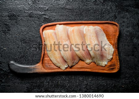 Fish fillet on a wooden cutting Board. On black rustic background