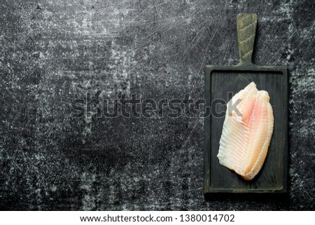 Fish fillet on a black cutting Board. On black rustic background