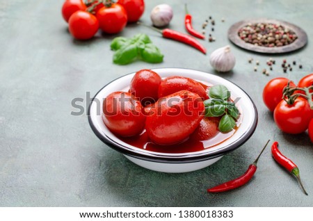 Whole canned tomatoes in their own juice with spices on a green slate background. Selective focus.