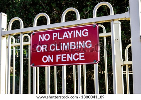 red warning sign no playing or climbing on fence