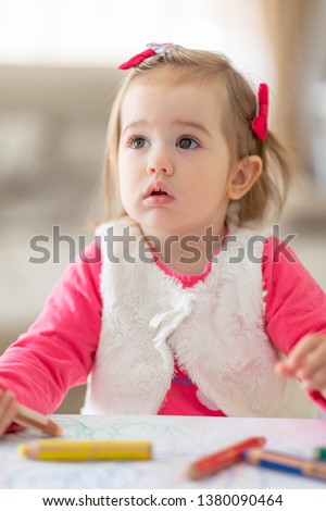 Cute little girl drawing, closeup portrait. Happy and smart little girl before table with colorful pencils