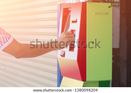 ็Hand dropping a coin into a vending machine top-up for   phones.   isolated on white background.