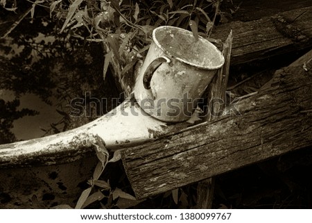 Rural farm. Mug for watering plants in the garden. Picture taken in Ukraine. Kiev region. Horizontal frame. Black and white image. Sepia. Tint of silver