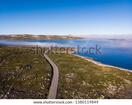 Aerial view. Road crossing Hardangervidda mountain plateau, clouds over lakes, morning time. Norway landscape. National tourist Hardangervidda route. Royalty-Free Stock Photo #1380119849