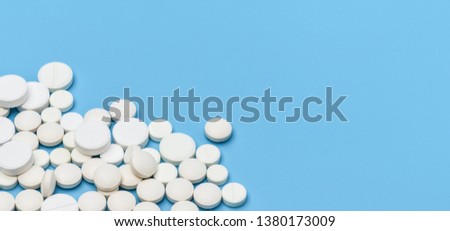 Lots of white pills on blue background. Medical concept
