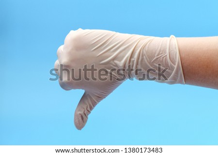 Medical glove shows thumb down on a blue background