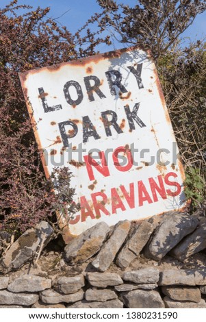 An old sign at the entrance to a lorry park, with the instruction that no caravans are allowed.