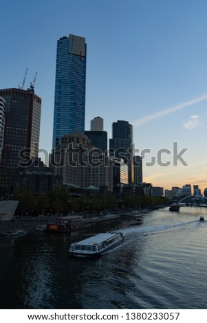 The sun sets with a view of the Eureka Tower on the river bank 