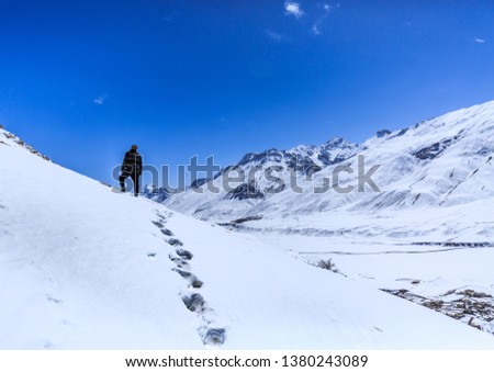 wanderlust trekker standing on peak of snow capped mountain with his foot prints left behind in winter
