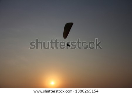 A paraglider against the background of the sea and sunset or dawn. Beautiful seascape. Extreme sport. The paraglider flies over the sea. India, Goa.