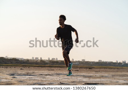 Picture of a handsome young african strong sports man running outdoors.