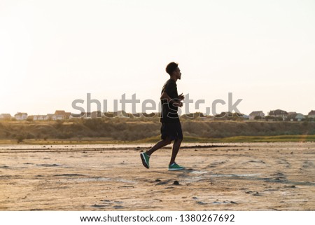 Picture of a handsome young african strong sports man running outdoors.