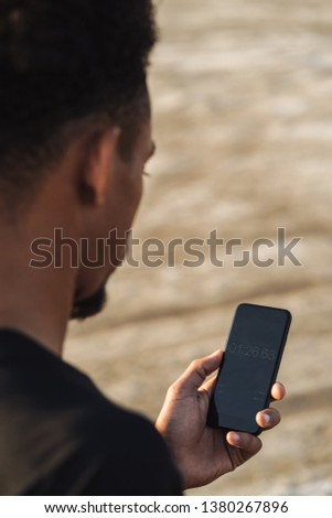 Cropped picture of a handsome young african strong sports man using mobile phone outdoors.