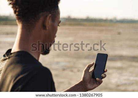 Cropped picture of a handsome young african strong sports man using mobile phone outdoors.