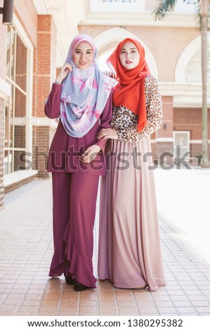 Beautiful Muslim girlfriends looking over urban background . friendship concepts