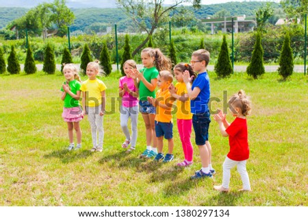Group of kids clapping hands on the green grass