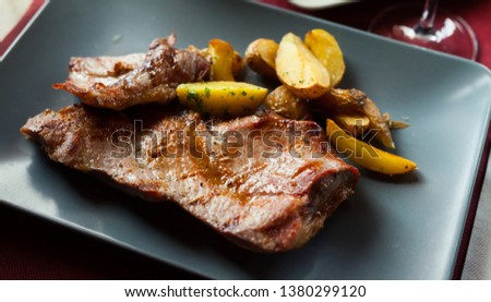 Picture  of delicious fried iberian pork with  fried potatoes at plate on table