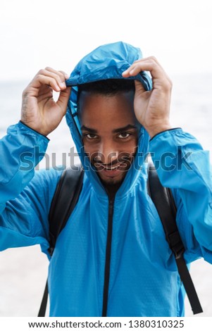 Picture of a handsome young african sports man outdoors at the beach sea walking with bag.