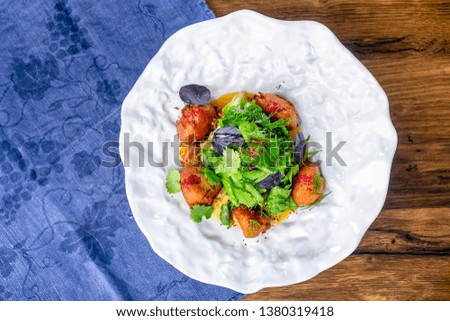 Salad with crispy chicken and sour pumpkin cream. European cuisine. The work of a professional chef. Dish from a restaurant or cafe menu. Close-up.