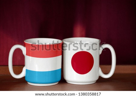 Japan and Luxembourg flag on two cups with blurry background