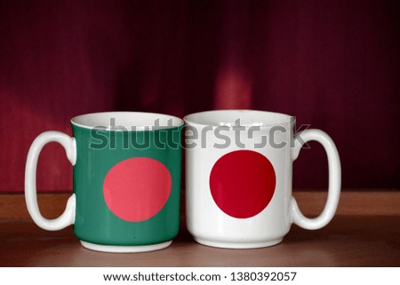 Japan and Bangladesh flag on two cups with blurry background