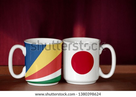 Japan and Seychelles flag on two cups with blurry background