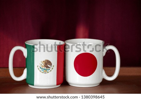 Japan and Mexico flag on two cups with blurry background