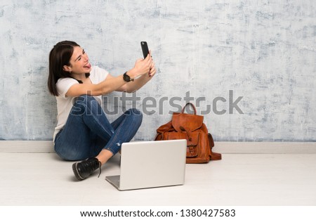 Student woman sitting on the floor making a selfie