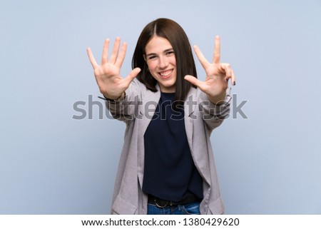 Young woman over isolated blue wall counting eight with fingers