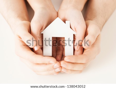 pisture of man and woman hands holding paper house