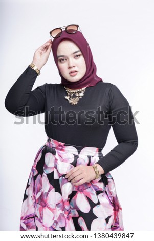 Beautiful Muslim female model wearing floral skirt, black shirt with hijab, isolated over white background. Eidul fitri fashion and beauty.