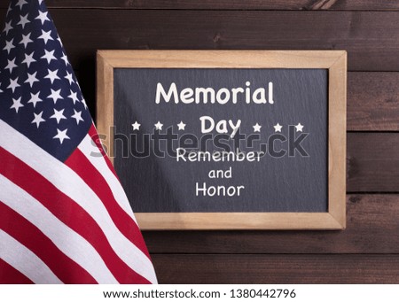 Memorial day remember and honor written on a clalkboard next to the american flag