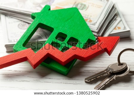 Up arrow and house with money on white wooden background. Market growth in real estate prices.