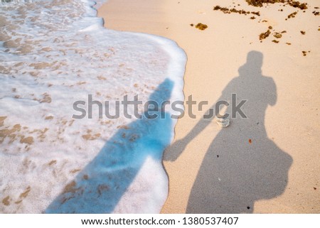 shadow couple hold hand background is the ocean wave on sandy beach