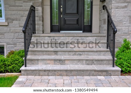Square cut flagstone applied to the original concrete veranda and steps, and a tumbled paver landing all provide a beautiful, fresh landscape update to this mid century modern bungalow. Royalty-Free Stock Photo #1380549494