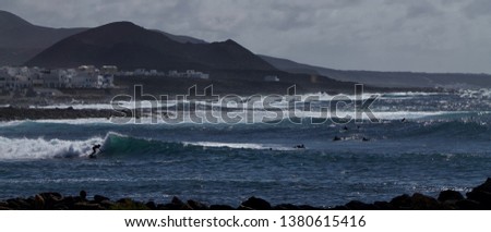 Panoramic picture with surfers and in the background volcanoes and the La Santa village in Lanzarote in the canary islands