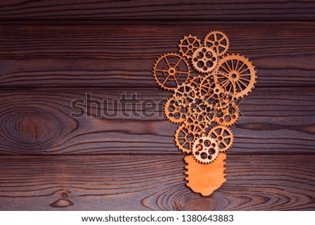 Light bulb made of wooden gears on the background of a wooden table. The concept of creativity, the business idea.