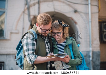 A young couple of tourists are looking for a road with a map in their hands in the city. The guy and the girl walk in a large European city with a map in their hands. 