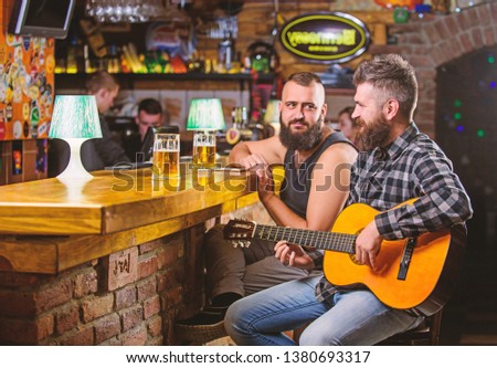 Cheerful friends relax with guitar music. Friday relaxation in bar. Friends relaxing in bar or pub. Real men leisure. Hipster brutal bearded spend leisure with friend in bar. Man play guitar in bar.